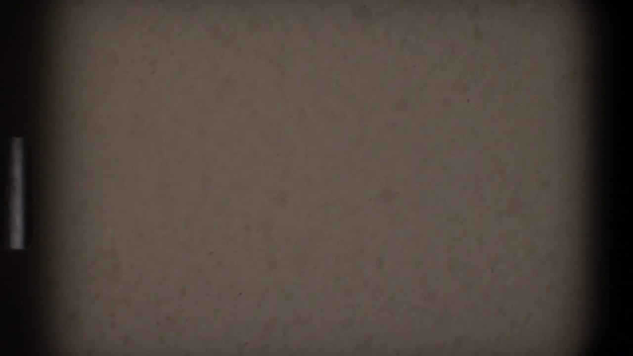 Blank pale film frame with heavy grain, dark side borders, and a small bright edge mark.