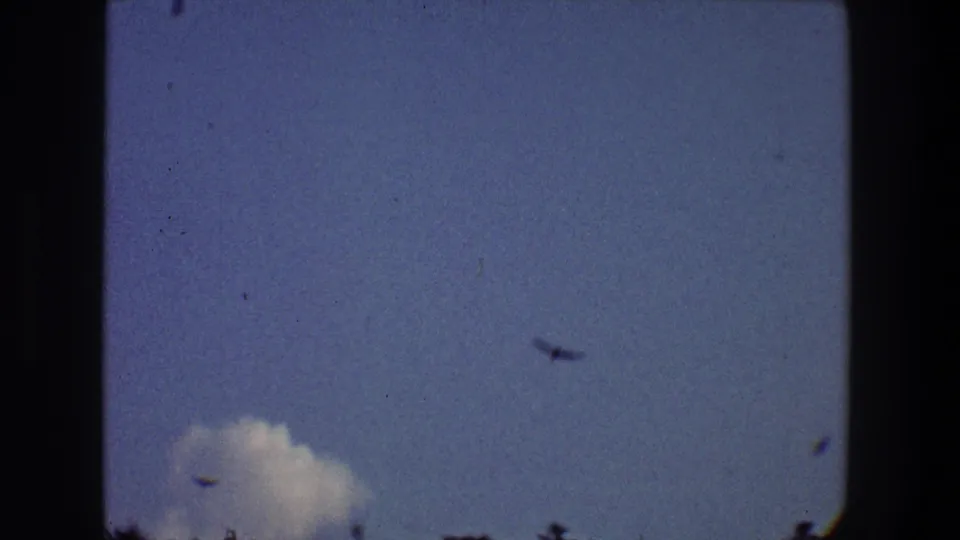 1968 Toledo 8mm frame showing birds in flight against blue sky above a small cloud and tree silhouettes.
