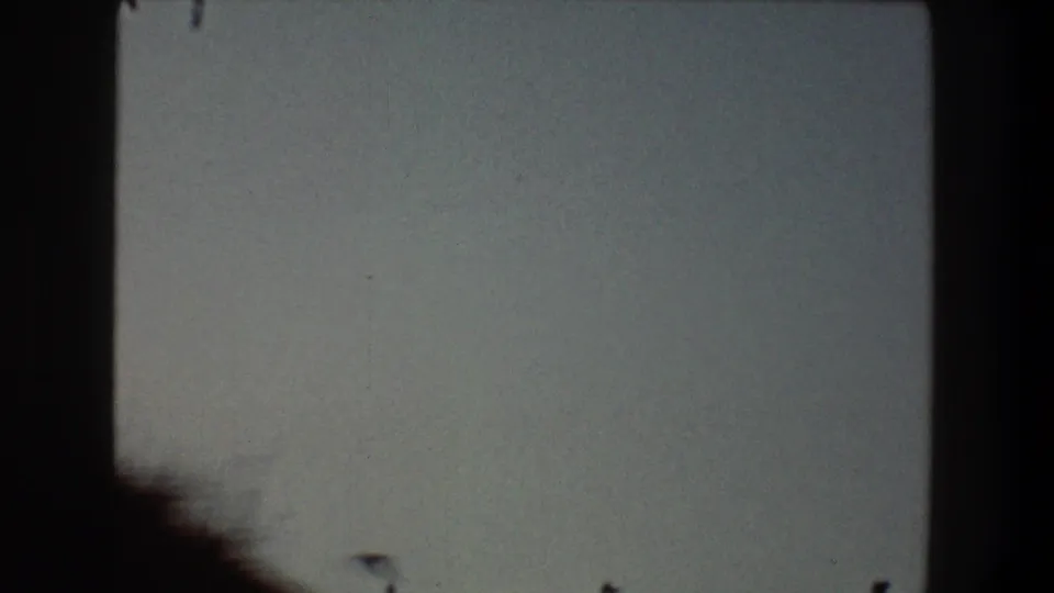 1968 Toledo 8mm frame with pale sky, a dark vertical border at left, and a soft dark shape near the bottom edge.