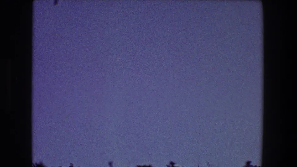 1968 Toledo 8mm frame showing blue sky with a low dark treetop silhouette and visible film grain.