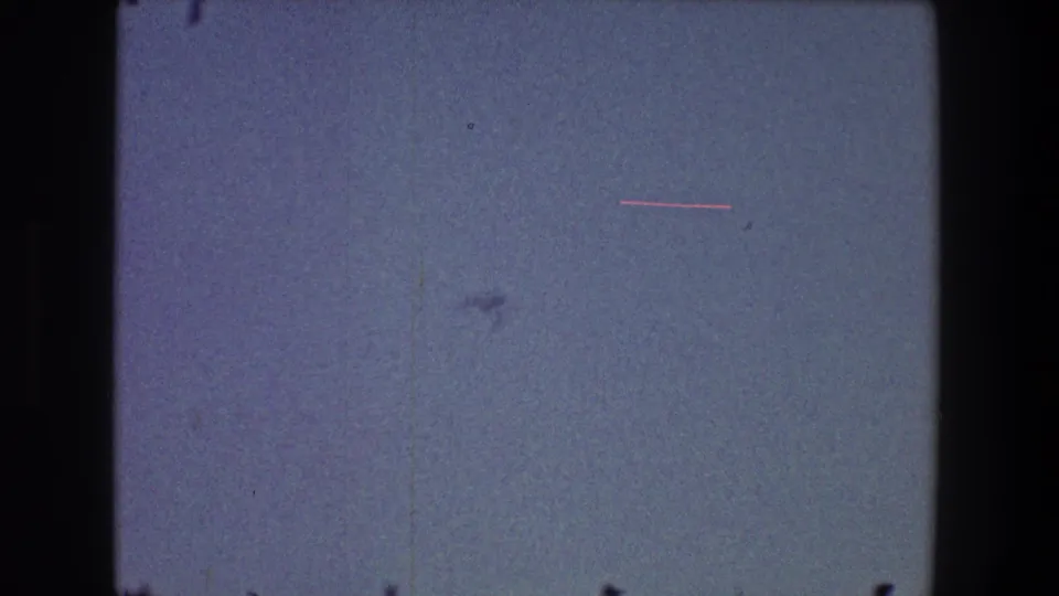 1968 Toledo 8mm frame showing mostly blue-gray sky, film dust, and dark gate borders with no identifiable people or buildings.