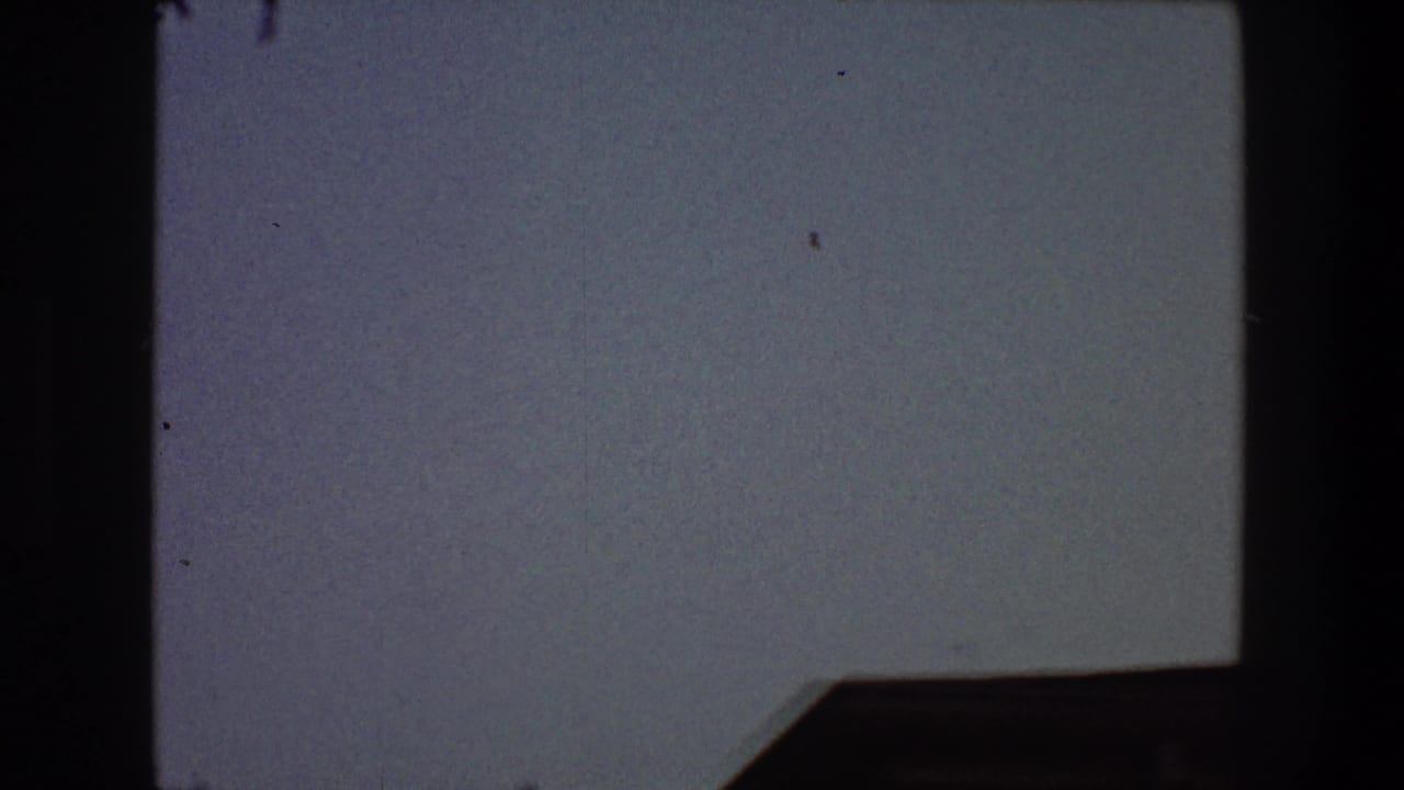 Open blue-gray sky with dark frame edges and a dark angular shape at the lower right.