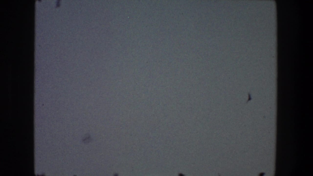 Dim sky with film gate edges and faint dark specks near the frame.