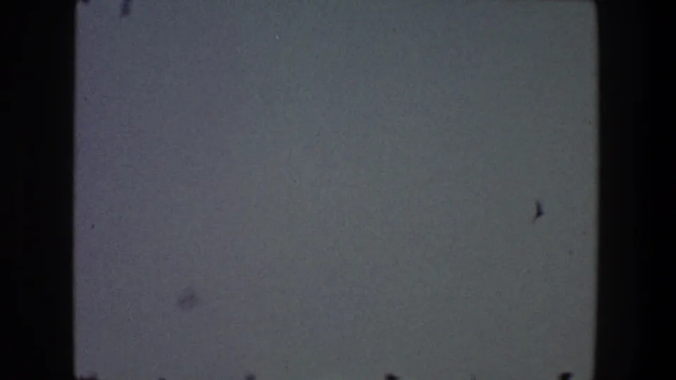 1968 Toledo home-movie frame showing a muted dusk sky with film borders, grain, and small dark marks or distant birds.