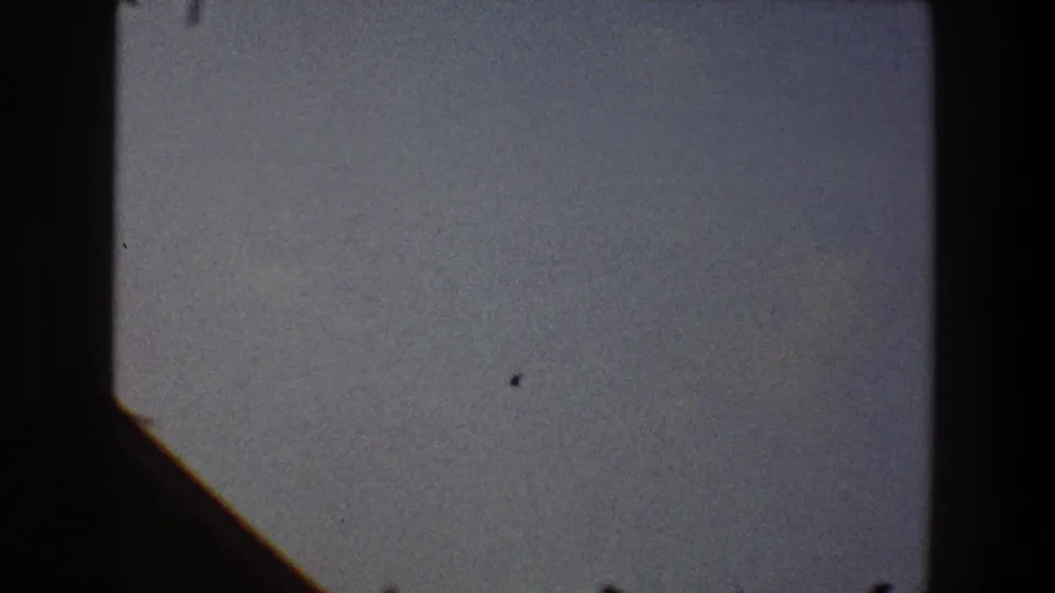 A pale evening sky appears above a dark sloping roofline in this 1968 Toledo 8mm frame, with grain and small film marks visible across the scan.