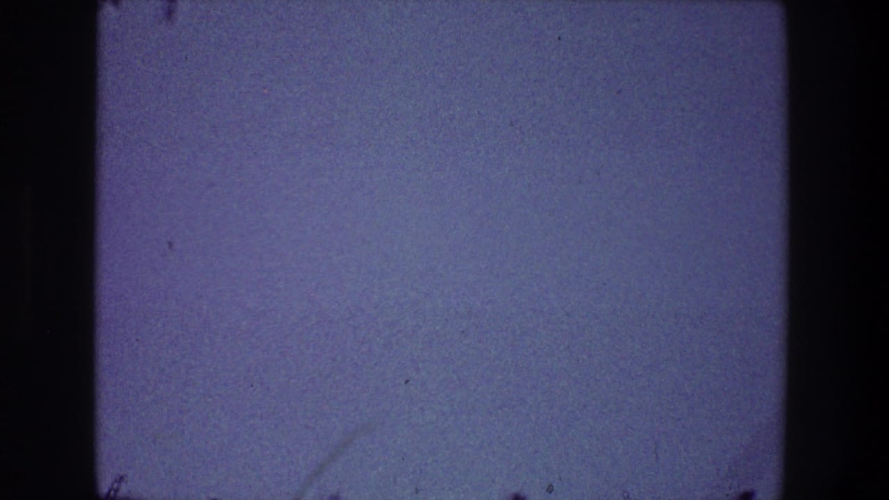 Open blue sky with dust specks, light scratches, and dark film borders.