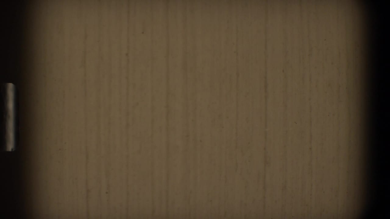 1968 Toledo 8mm frame showing a close-up wood-grain surface, heavy black vignette, and a narrow metal pull near the left edge.