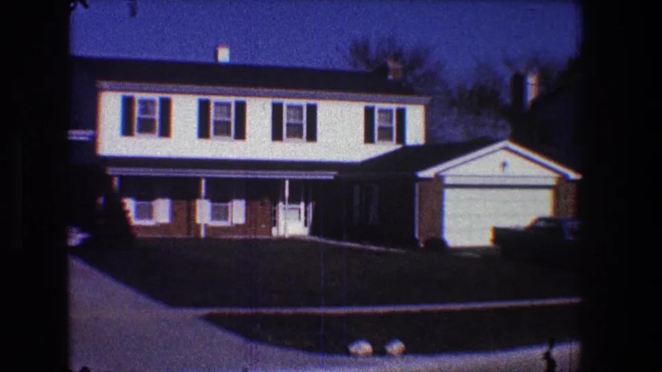 1968 Toledo home-movie view of a suburban split-level house, front lawn, sidewalk, driveway, and attached garage.