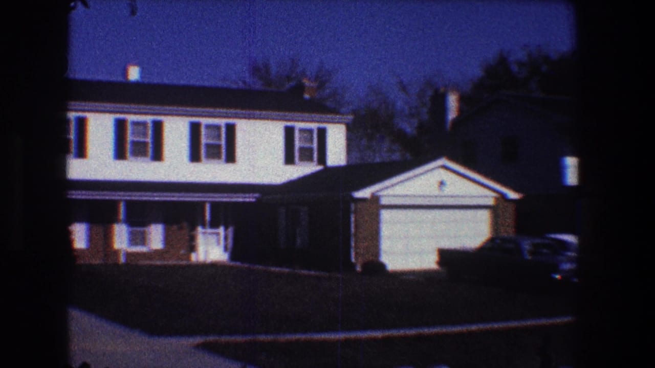 Suburban houses with garages and parked cars viewed across a residential street.