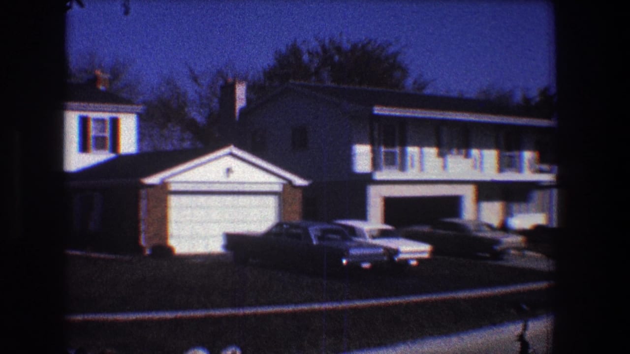 Two neighboring houses with garages and several cars parked near the driveways.