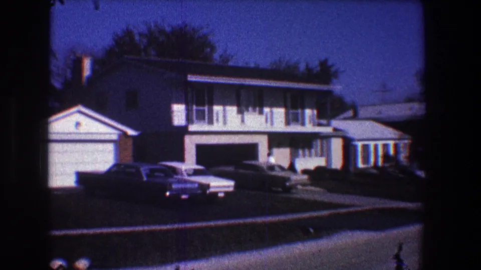 1968 Toledo frame of a two-story suburban home, attached garage, parked cars, sidewalk, and neighboring roofline.