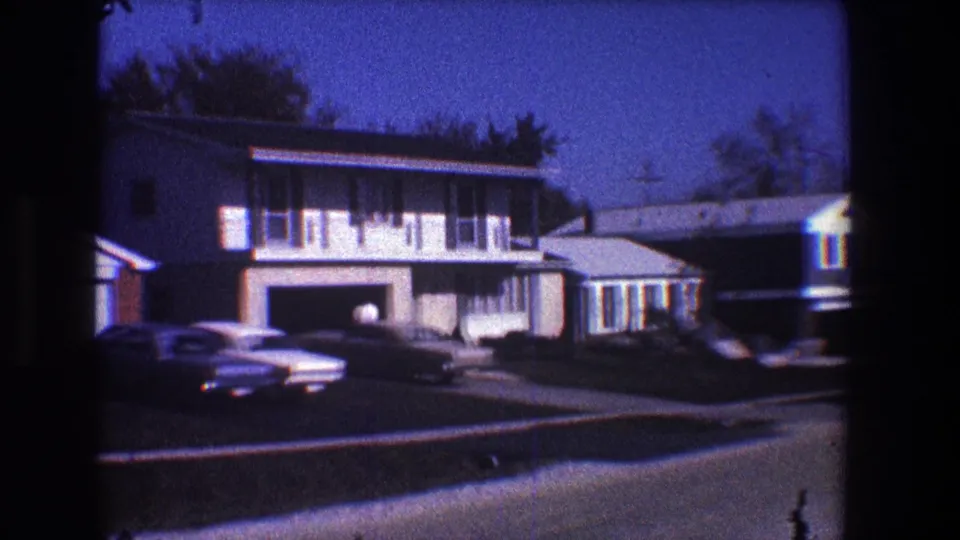 1968 Toledo home-movie view of a suburban house with attached garage, driveway cars, lawn, and nearby homes.