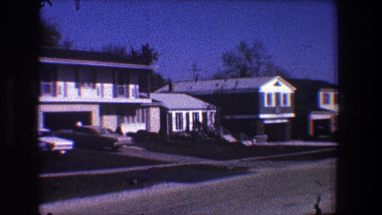 Suburban houses and parked cars along a quiet residential street.