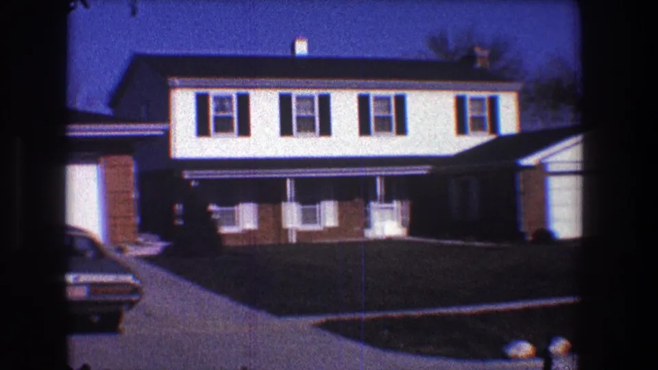 1968 Toledo home exterior with a two-story house, attached garage, front lawn, driveway, and part of a parked car in frame.