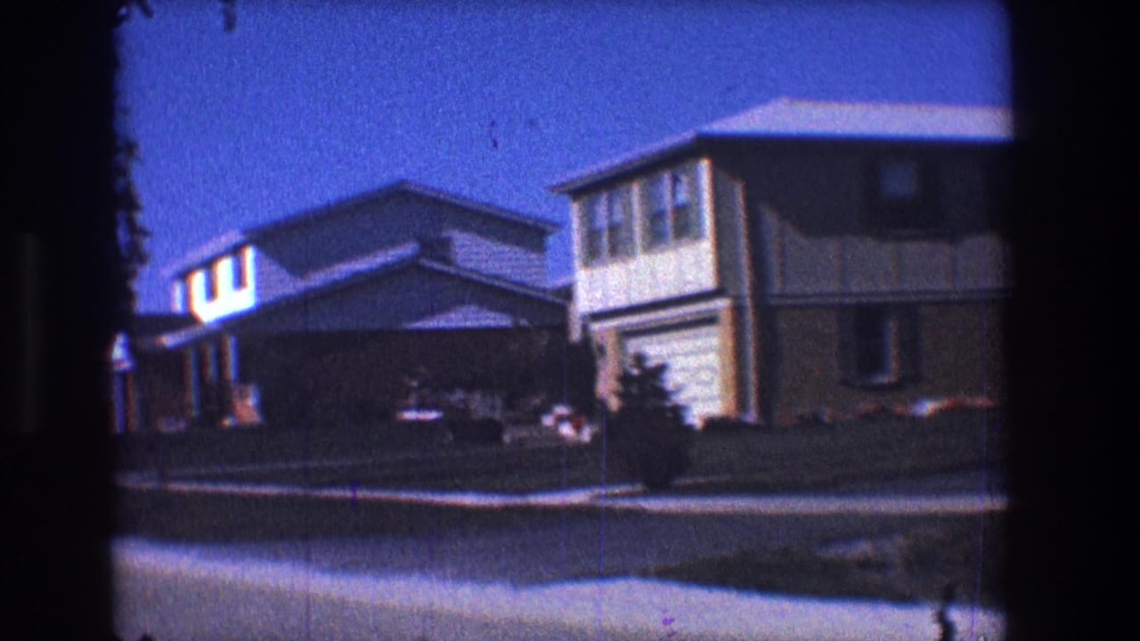 Residential street view with houses, lawns, and a driveway.