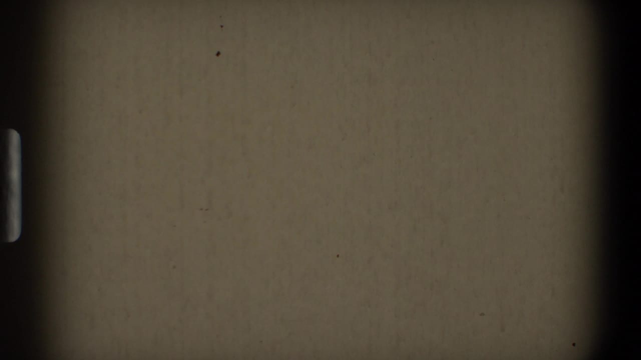 Blank 8mm film frame with dark borders, grain, dust, and partial sprocket marks.