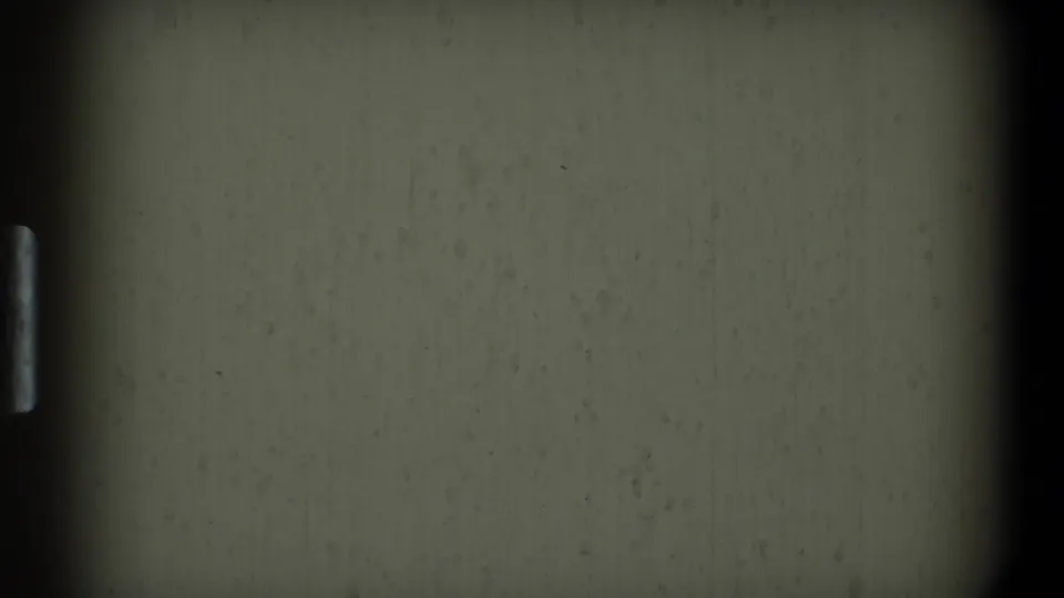 A plain textured wall appears between dark 8mm frame borders at the end of the Toledo home-movie clip.