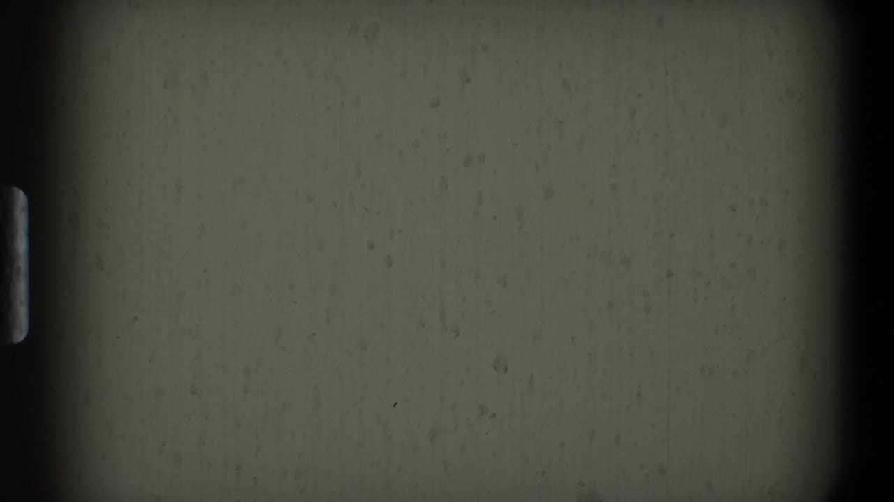 Gray film leader with dark vertical edge and surface specks.