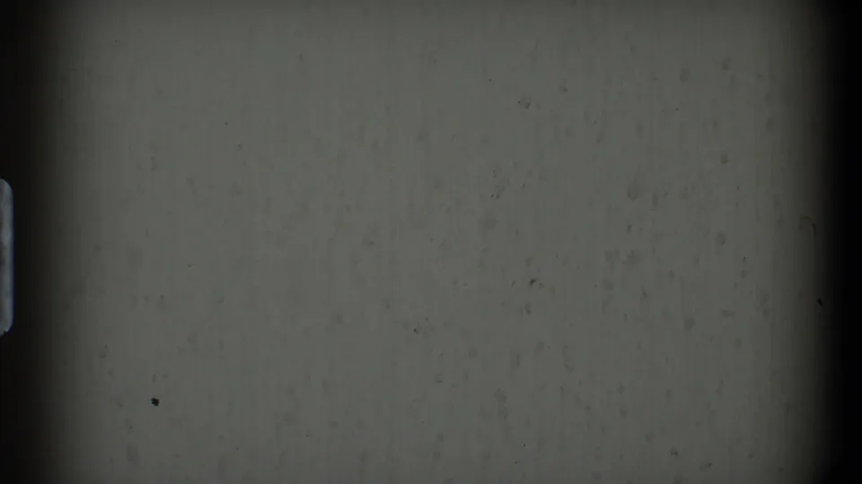 1968 Toledo home-movie frame showing a dim wall area with strong gate shadows and little visible room detail.