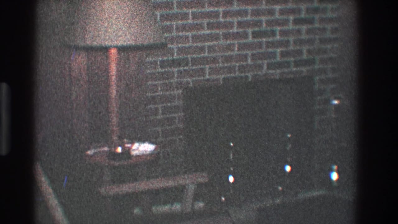 Floor lamp beside a brick fireplace with a dark hearth and small table below.