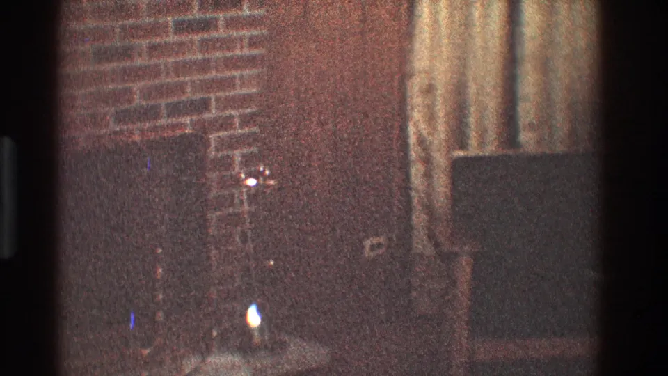 1968 Toledo living-room frame showing a brick fireplace edge, dark hearth, drapery, wood-toned wall area, and a small glow near the floor.