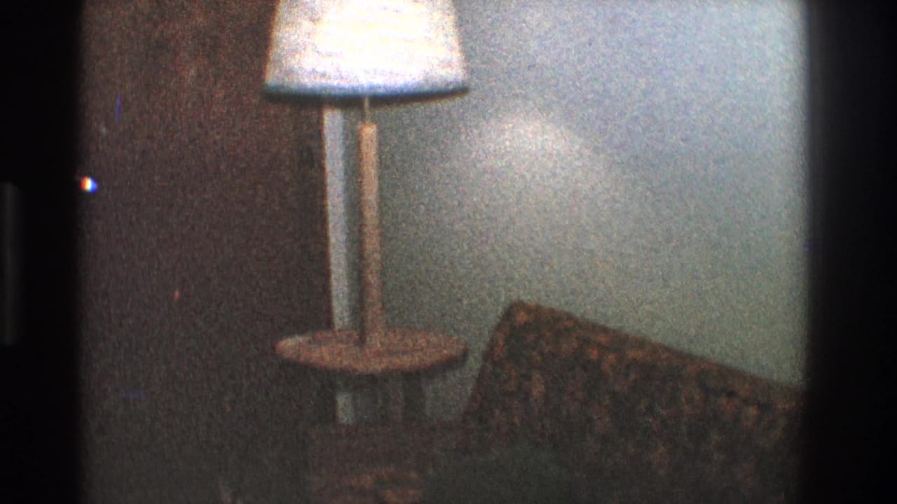 Patterned sofa beside a floor lamp with a small side table against a pale wall.