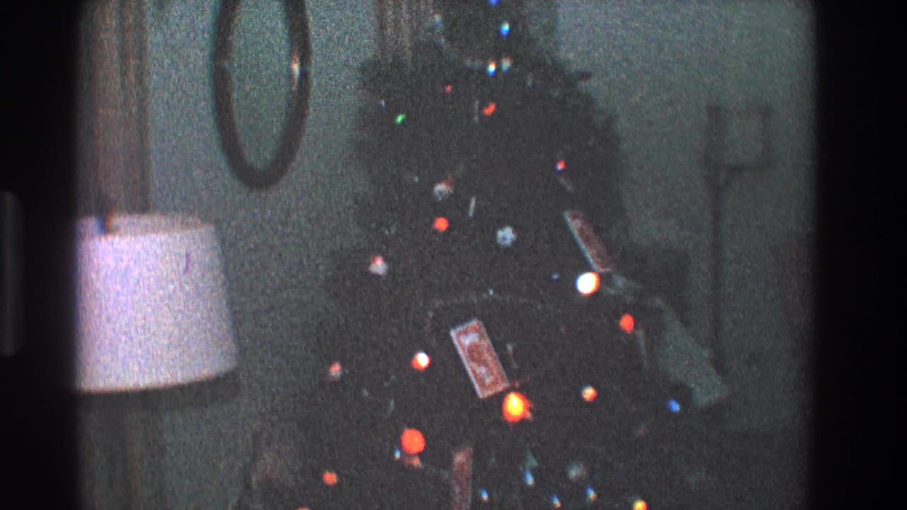 1968 Toledo interior frame with a soft, grainy view of a lit Christmas tree, ornaments, lamp, and circular mirror.