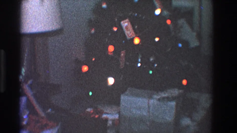 1968 Toledo frame showing a lit Christmas tree with ornaments and wrapped presents below, filmed in a grainy private living room interior.