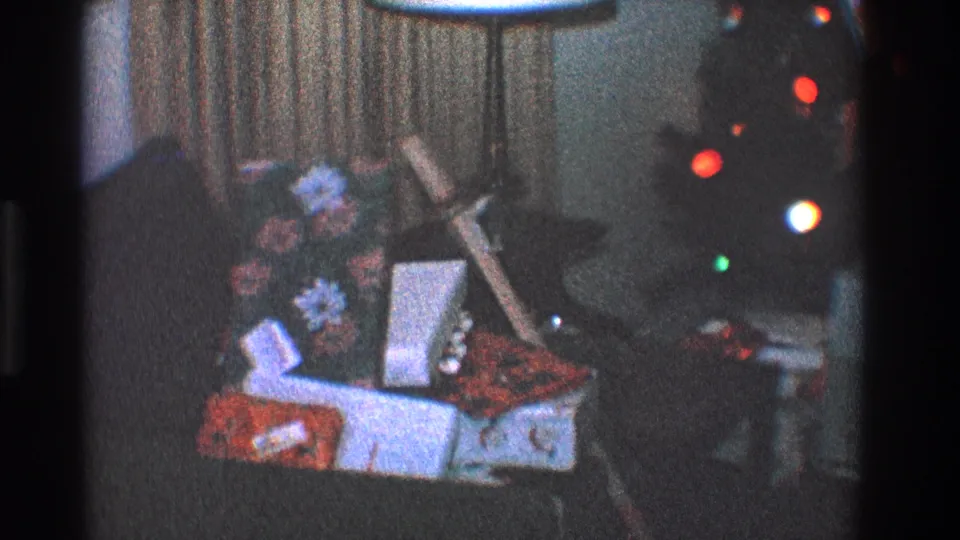 1968 Toledo living-room view with wrapped gifts, floral decor, curtains, and colored Christmas lights in the background.