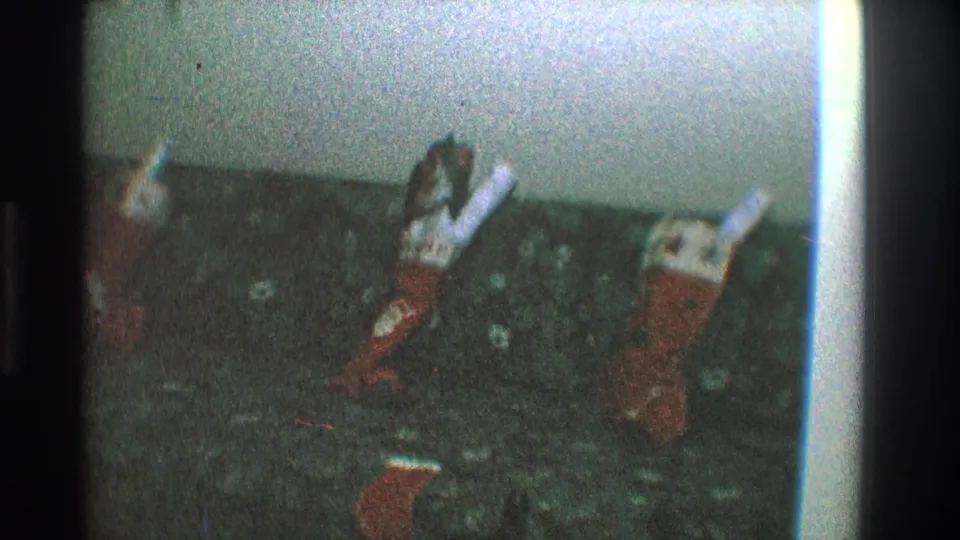 Final 1968 Toledo home-movie frame focused on several Christmas stockings hanging against a pale wall in a private interior.