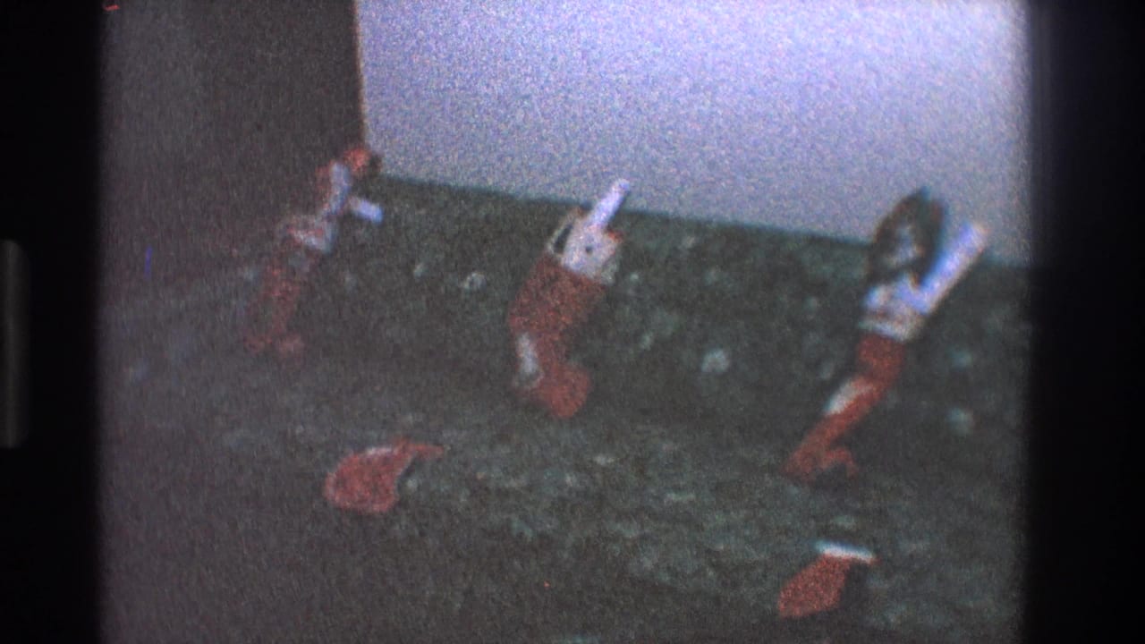 Several stuffed stockings rest against a dark couch, with one stocking lower in the frame.