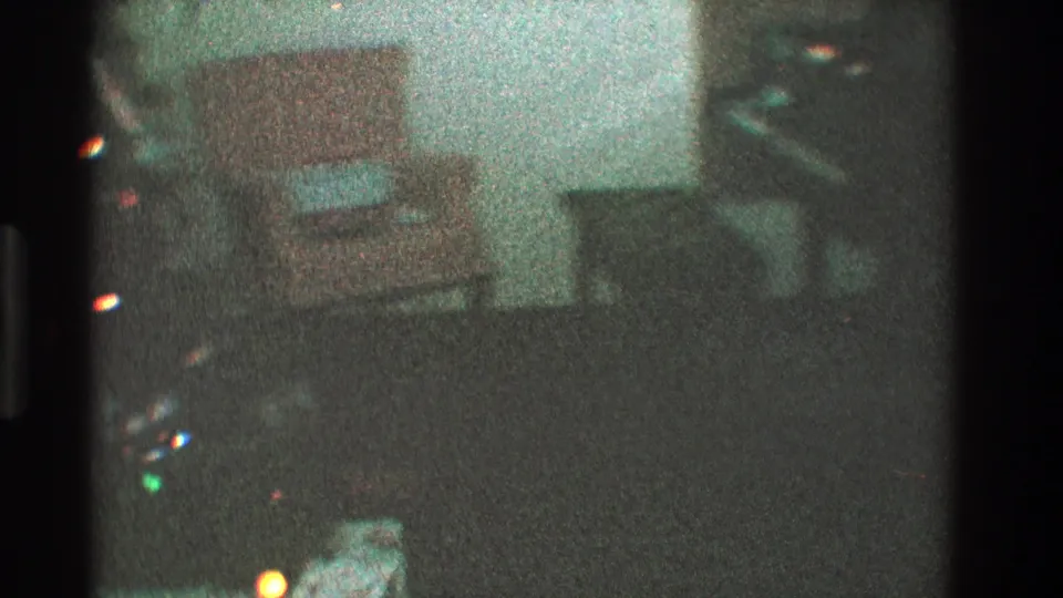 Low-light 1968 Toledo home-movie frame showing a pale orange armchair with a wrapped gift in a private living room.