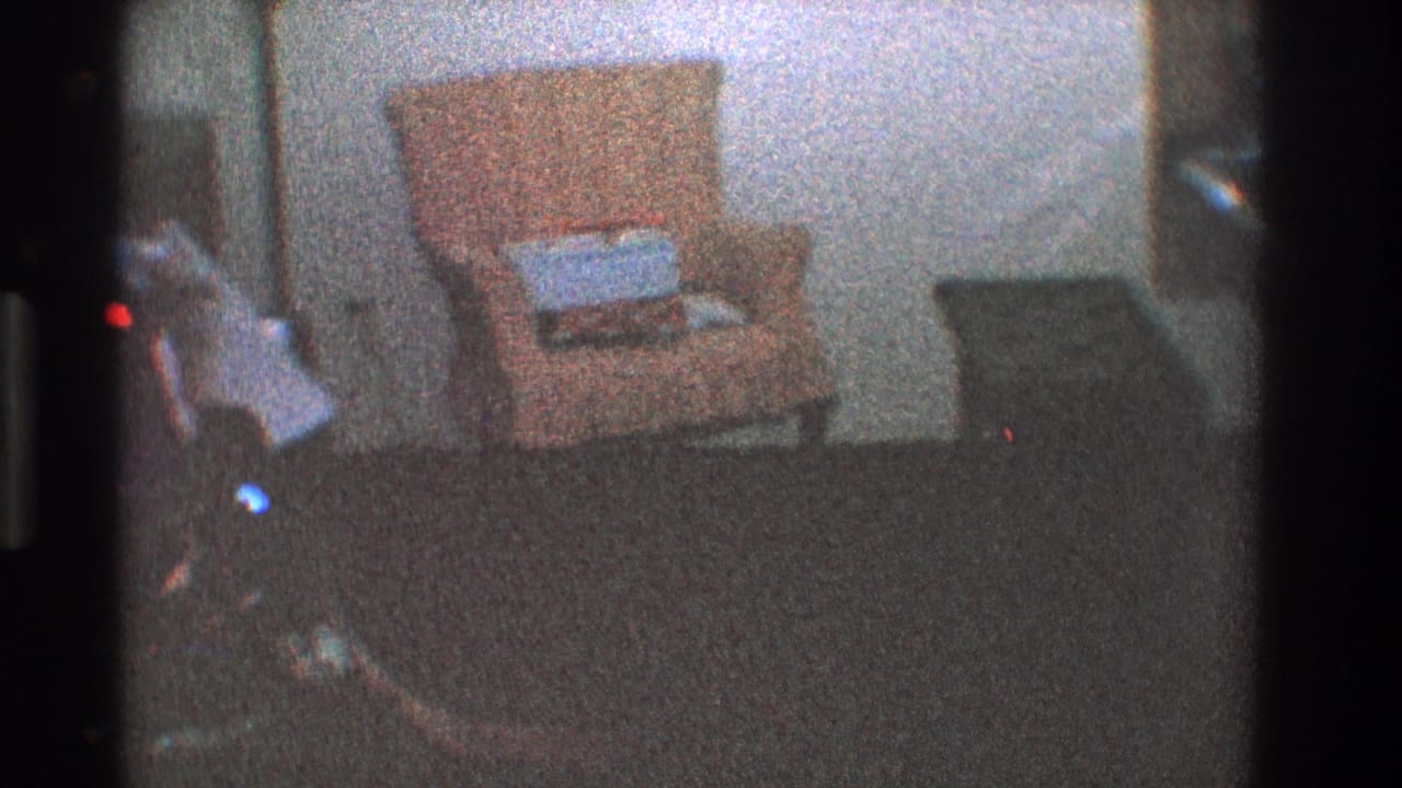 Pale orange chair with a gift on the seat beside darker furniture in a dim room.