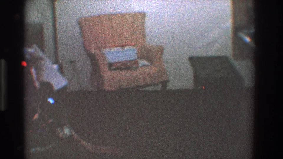 Dim 1968 Toledo living room view with a pale orange chair, wrapped gift, and dark furniture nearby.