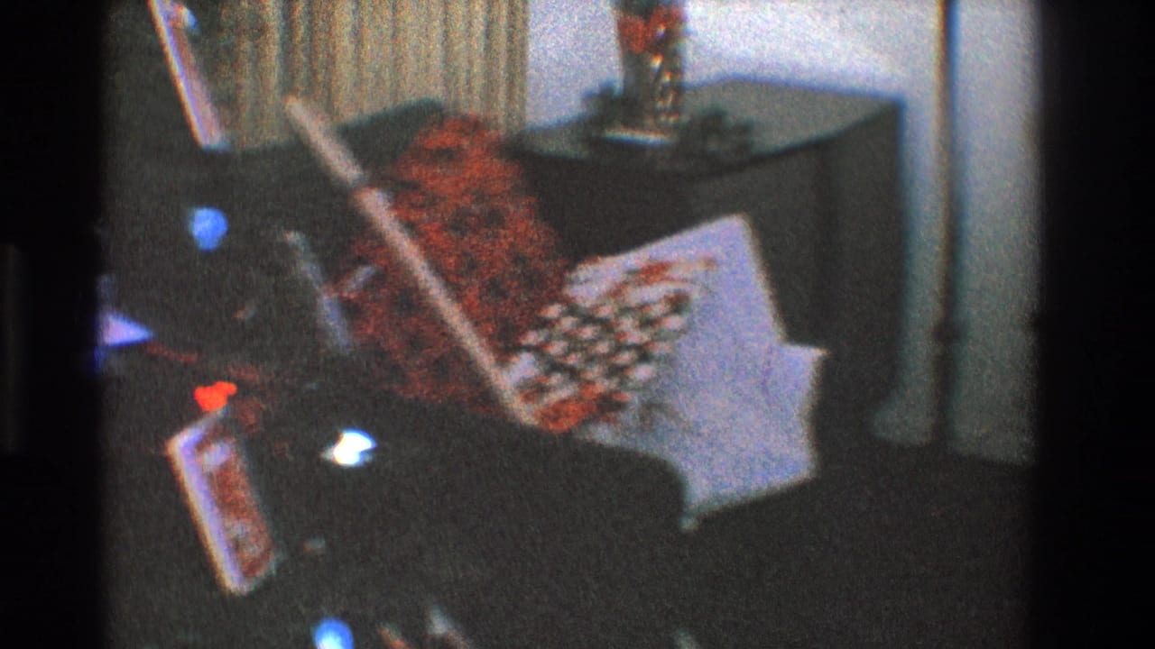 Wrapped gifts and a red patterned textile near a dark couch and curtains.