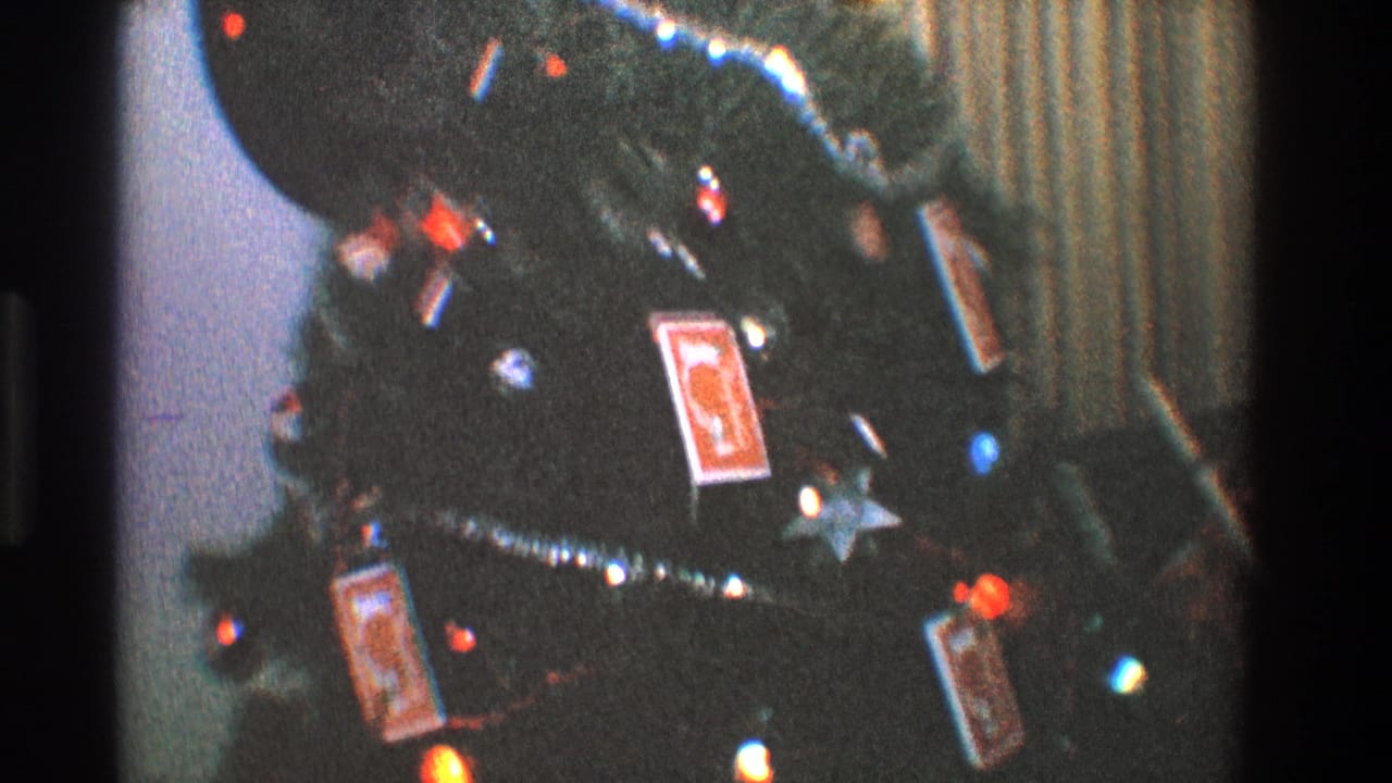 1968 Toledo 8mm frame showing a decorated Christmas tree with colored bulbs, silver tinsel, and playing-card ornaments.