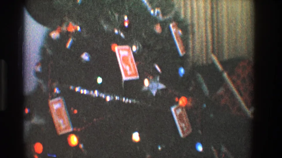 Close 8mm frame of a Toledo Christmas tree with bright colored bulbs, silver tinsel, hanging cards, and a small star ornament.