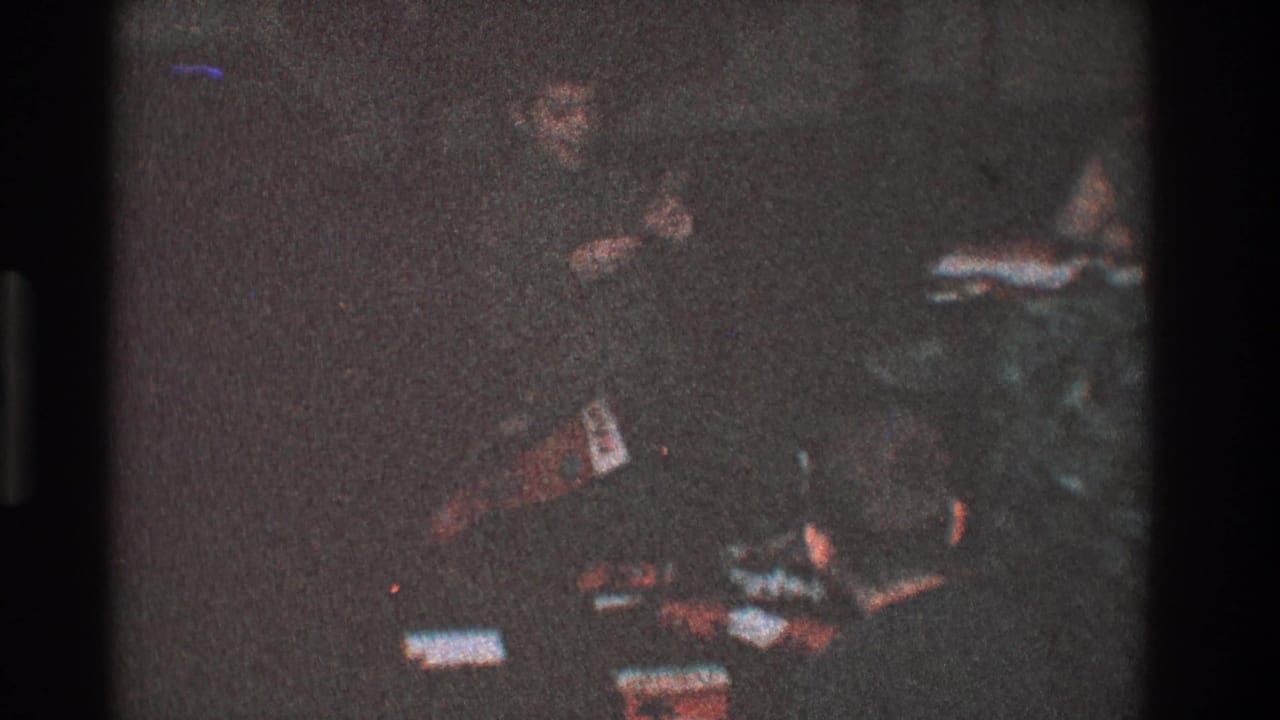 Child in a dim room near scattered objects on the floor.