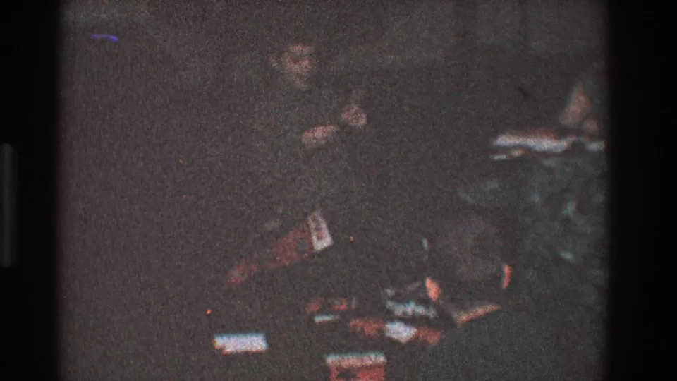 In 1968 Toledo home-movie footage, a child appears near scattered household items in a dark interior.
