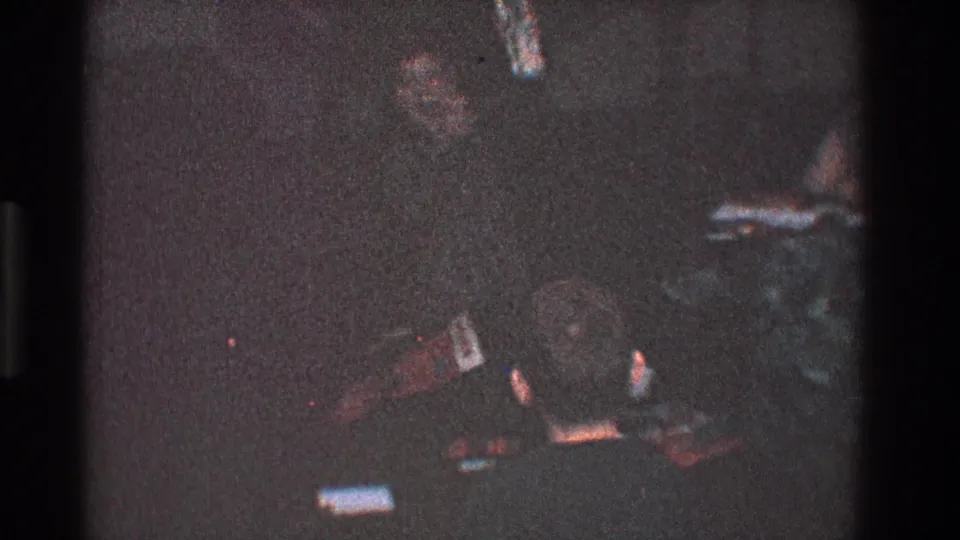 A grainy 1968 Toledo frame shows a child partly visible in a low-lit room with objects on the floor.