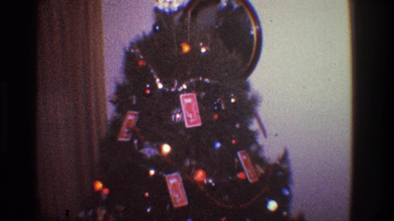 Christmas tree with glowing lights and card ornaments, framed beside a wall or doorway.