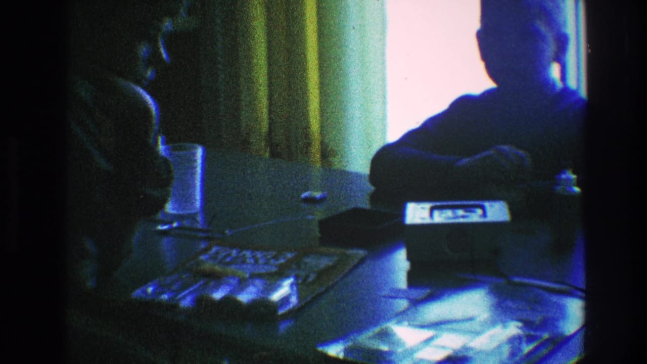 1968 Toledo home-movie frame showing a silhouetted seated figure at a glass table near a bright curtained window.