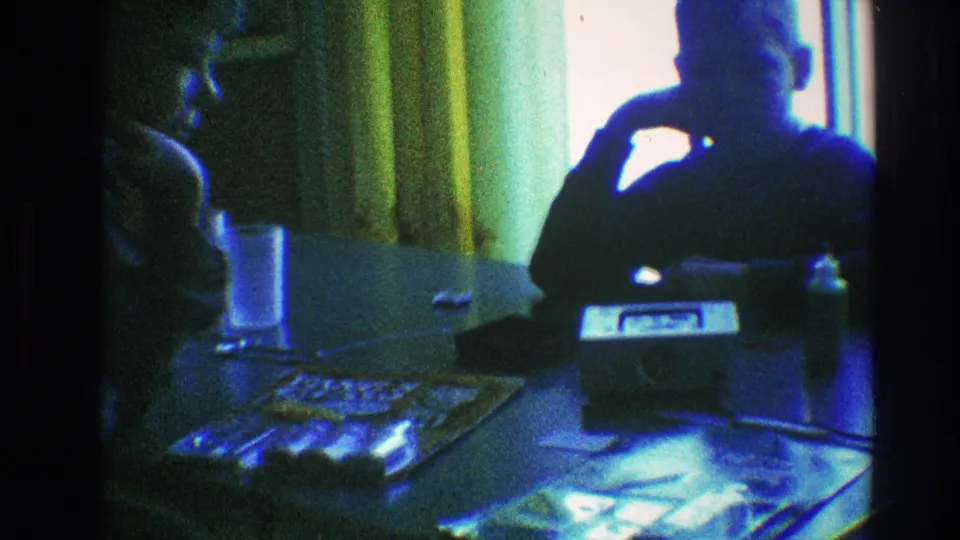 A final 1968 Toledo frame holds on two silhouetted people at a domestic table, backlit by a bright window and yellow curtains.