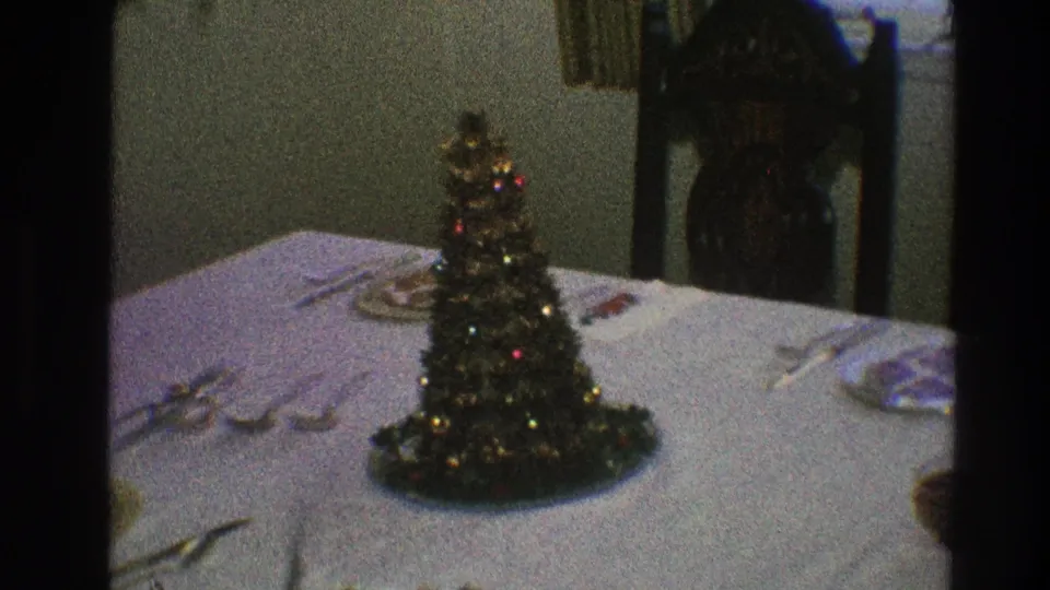 Soft 8mm frame showing a small decorated Christmas tree centered on a formal dining table in a private Toledo interior.