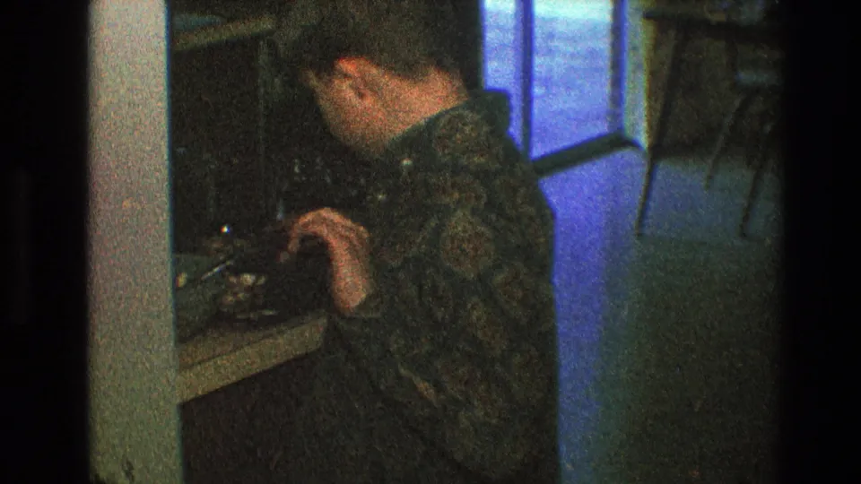 A boy appears beside dark cabinetry in the same 1968 Toledo home interior, with a window or bright blue light visible behind him.