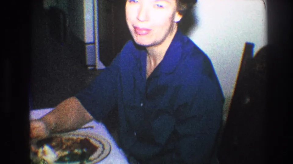 Older woman looks up toward the camera at a private dinner table in 1968 Toledo home-movie footage.
