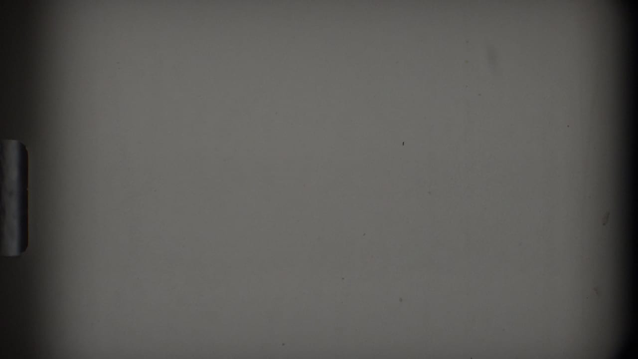 Dark framed view of a muted gray surface with a small vertical handle-like shape at the left edge.