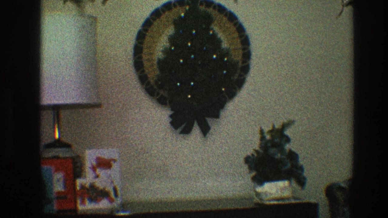 Wall wreath, table lamp, holiday cards, and small plant sit above and on a console table.