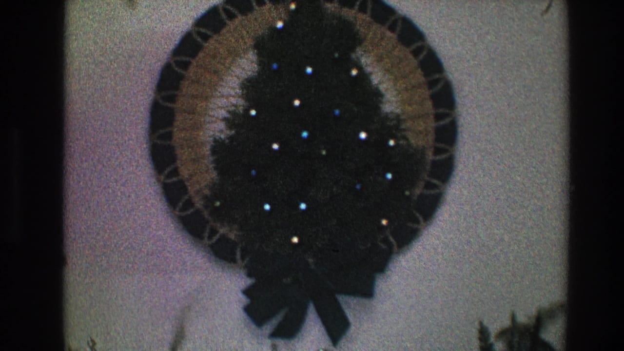 Circular Christmas wreath with small lights on a light wall.