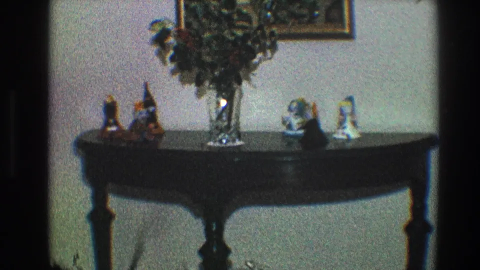1968 Toledo home interior with a dark console table, glass vase arrangement, small figurines, and framed picture.